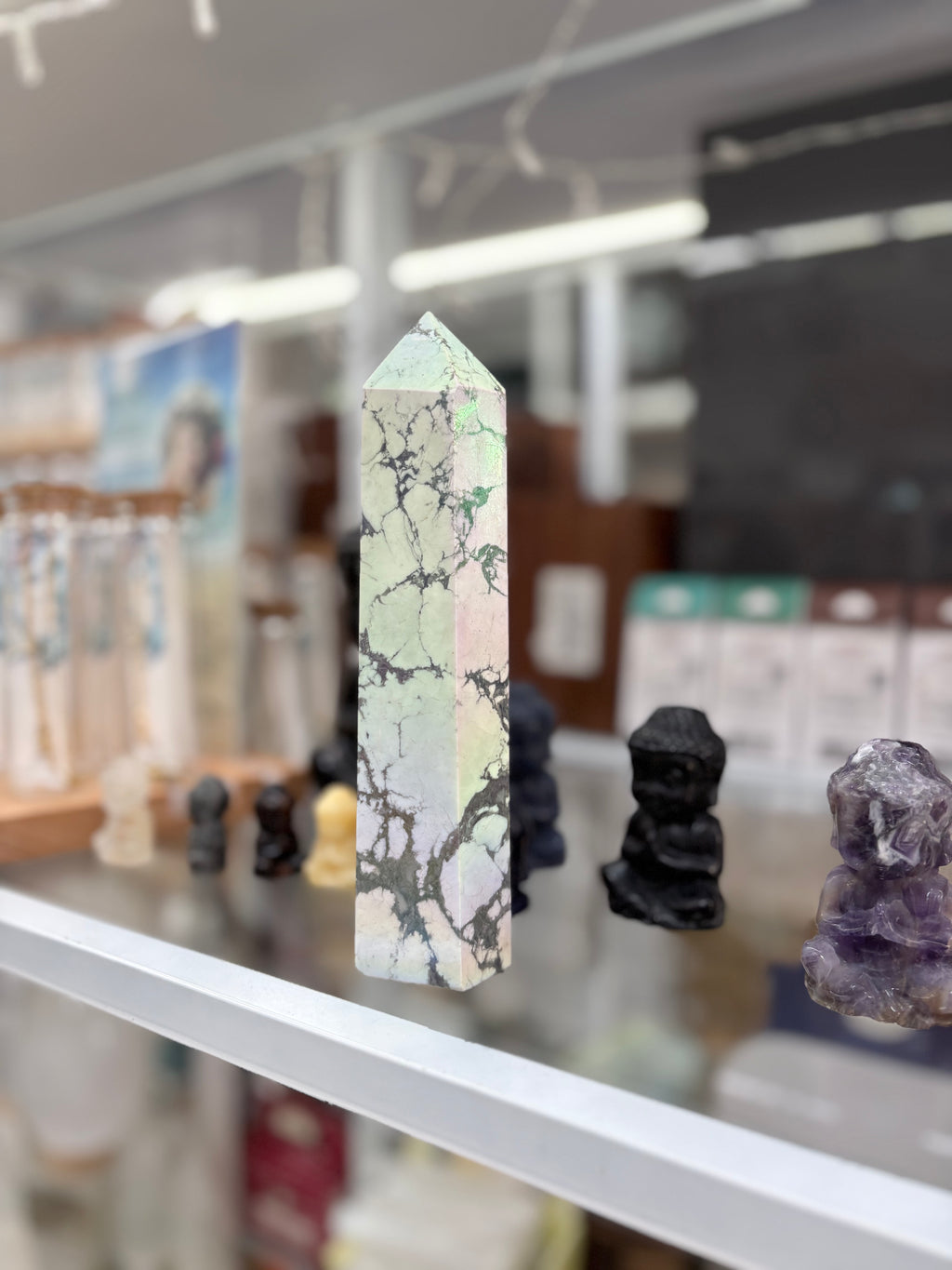 Marble-patterned crystal tower on a shelf with blurred background statement howlite