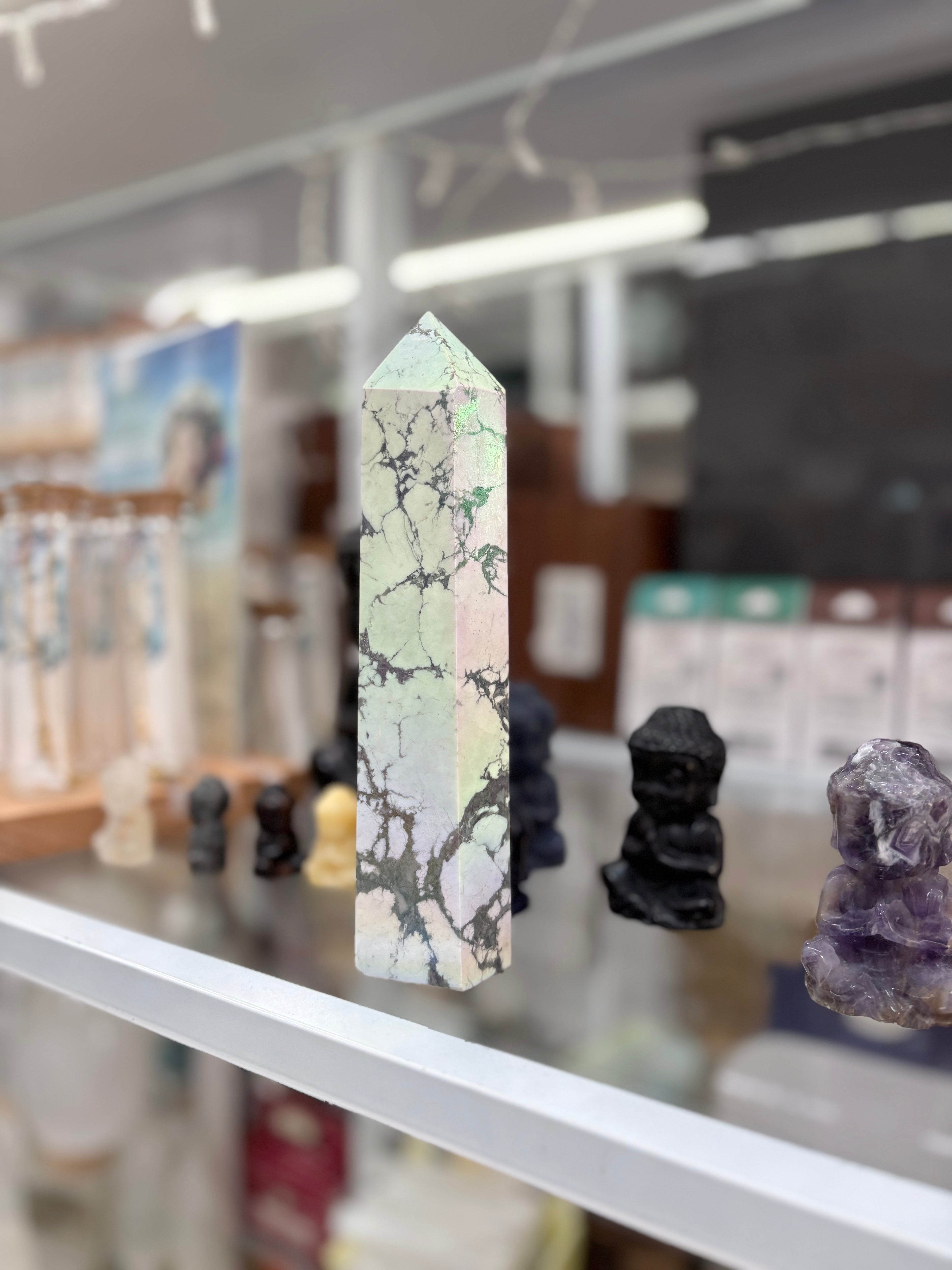 Marble-patterned crystal tower on a shelf with blurred background statement howlite