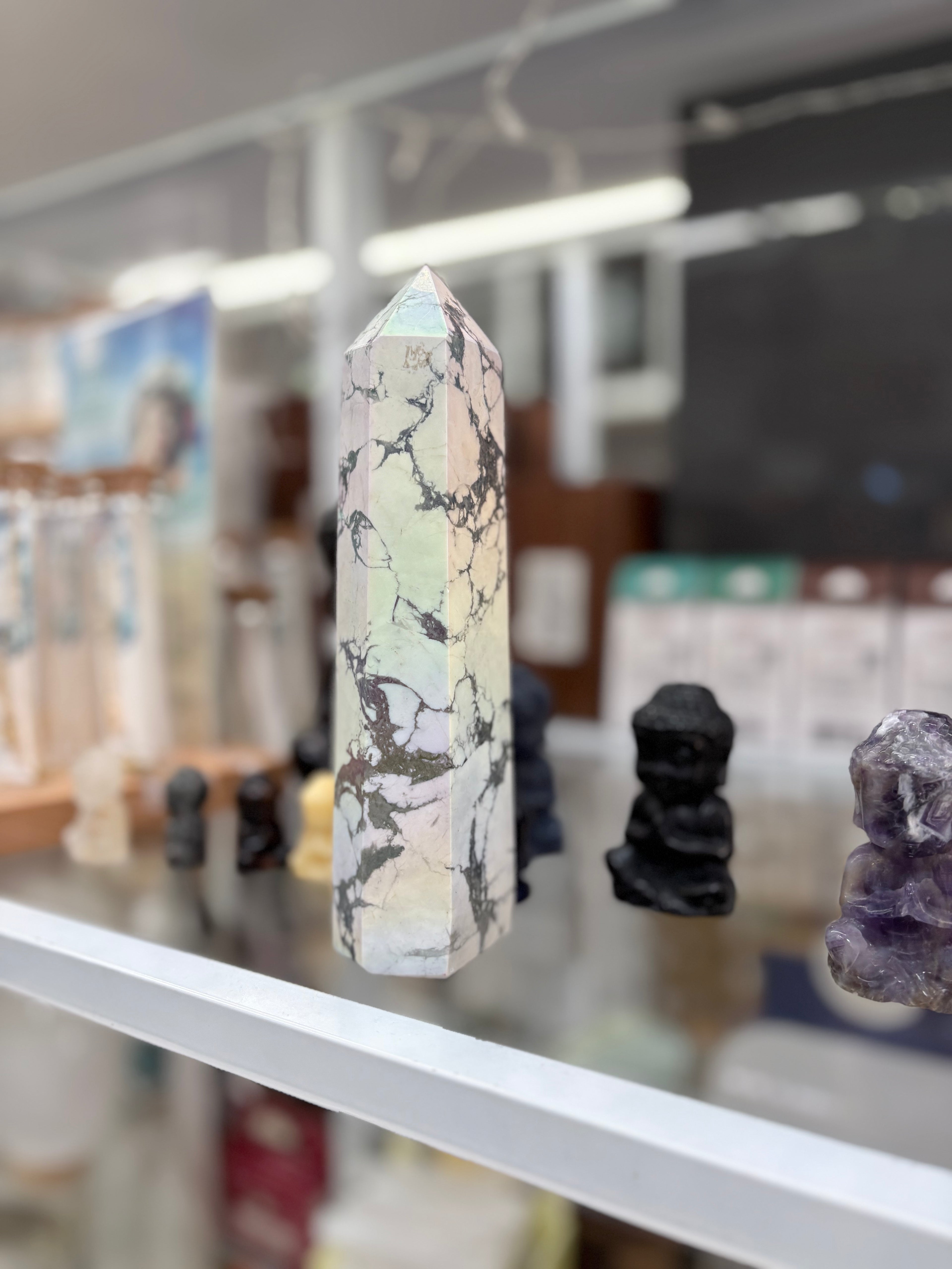 Marble-patterned crystal on a shelf with blurred background. statement howlite