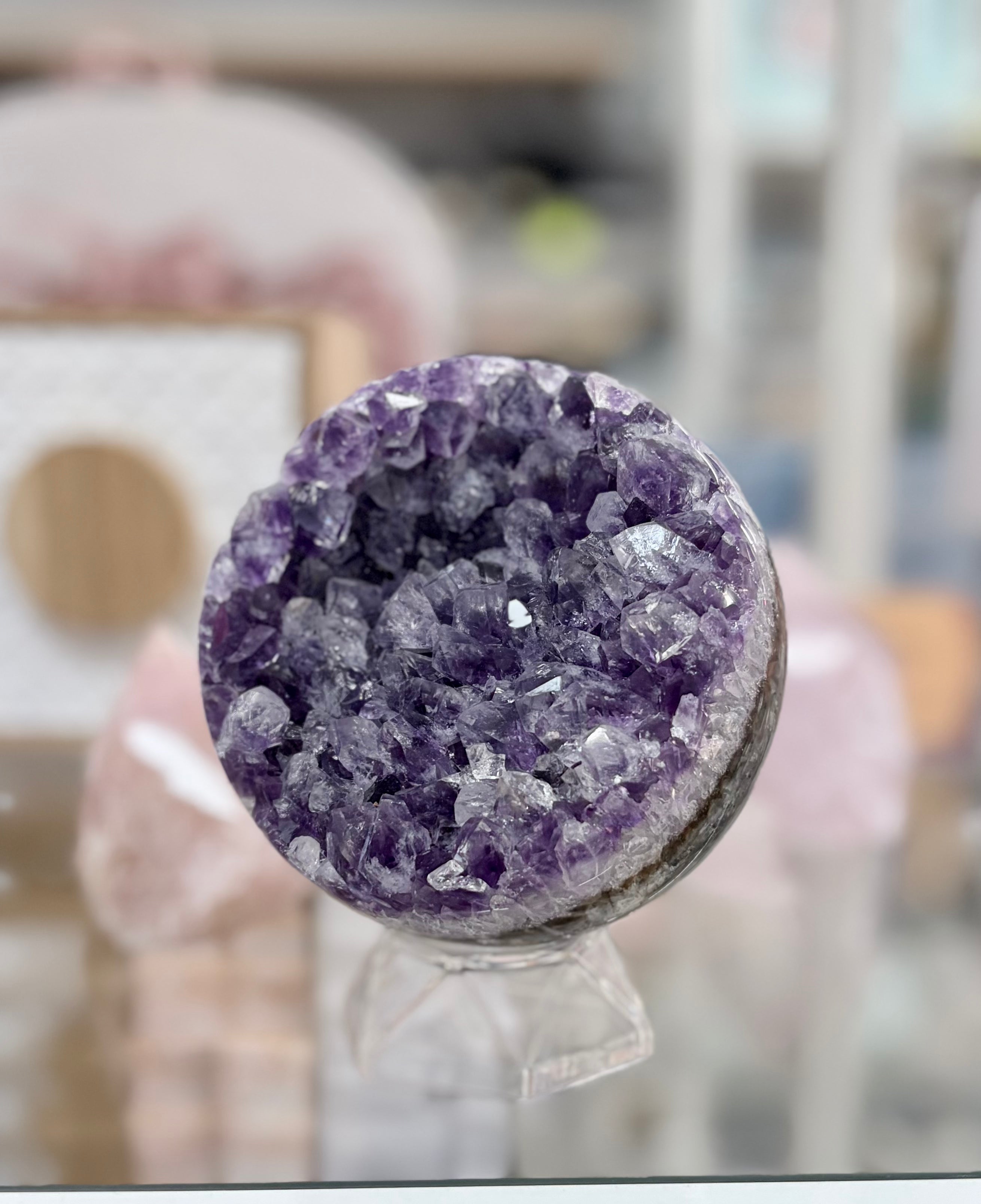 Amethyst geode on a stand with a blurred indoor background