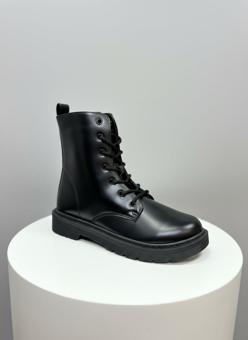 Black leather boot on a white pedestal with a light gray background